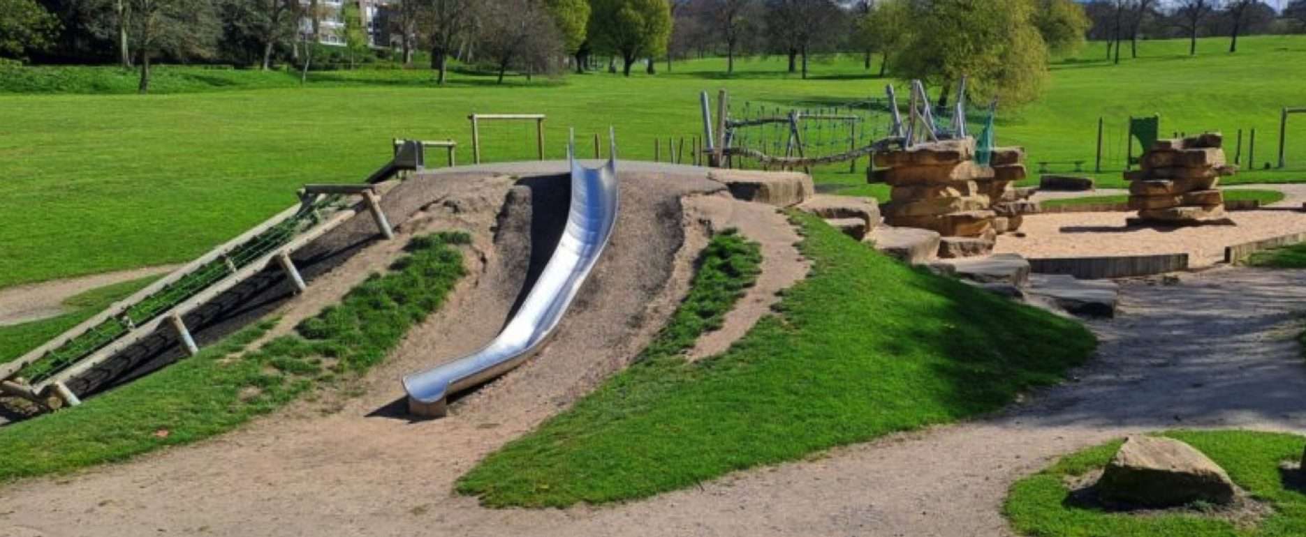 A large community park with well-laid-out paths, gardens, a small lake, play areas, a BMX track, and sports pitches.